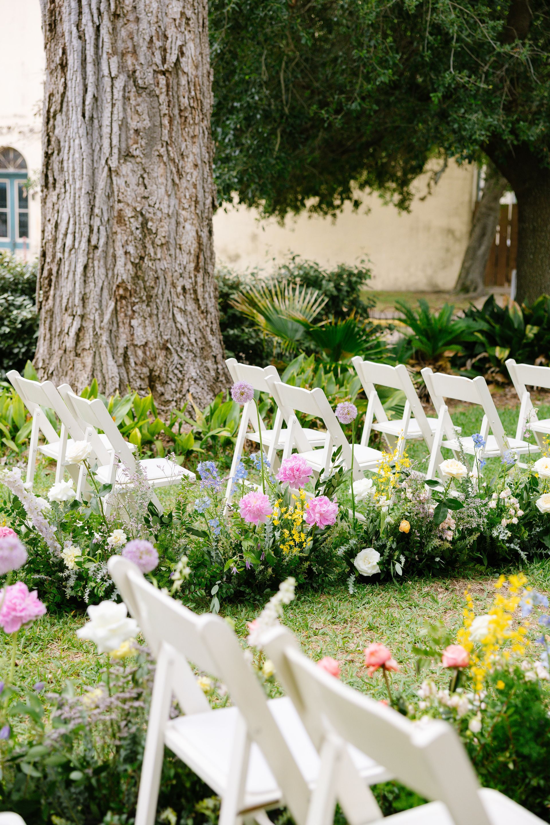 wedding aisle at outdoor garden ceremony space filled with flowers and white garden chairs in brenham at the Ant Street hotel