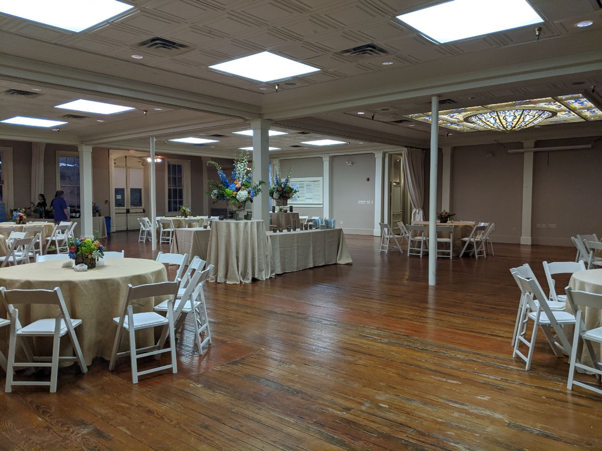 A large room with tables and chairs set up for a wedding reception.