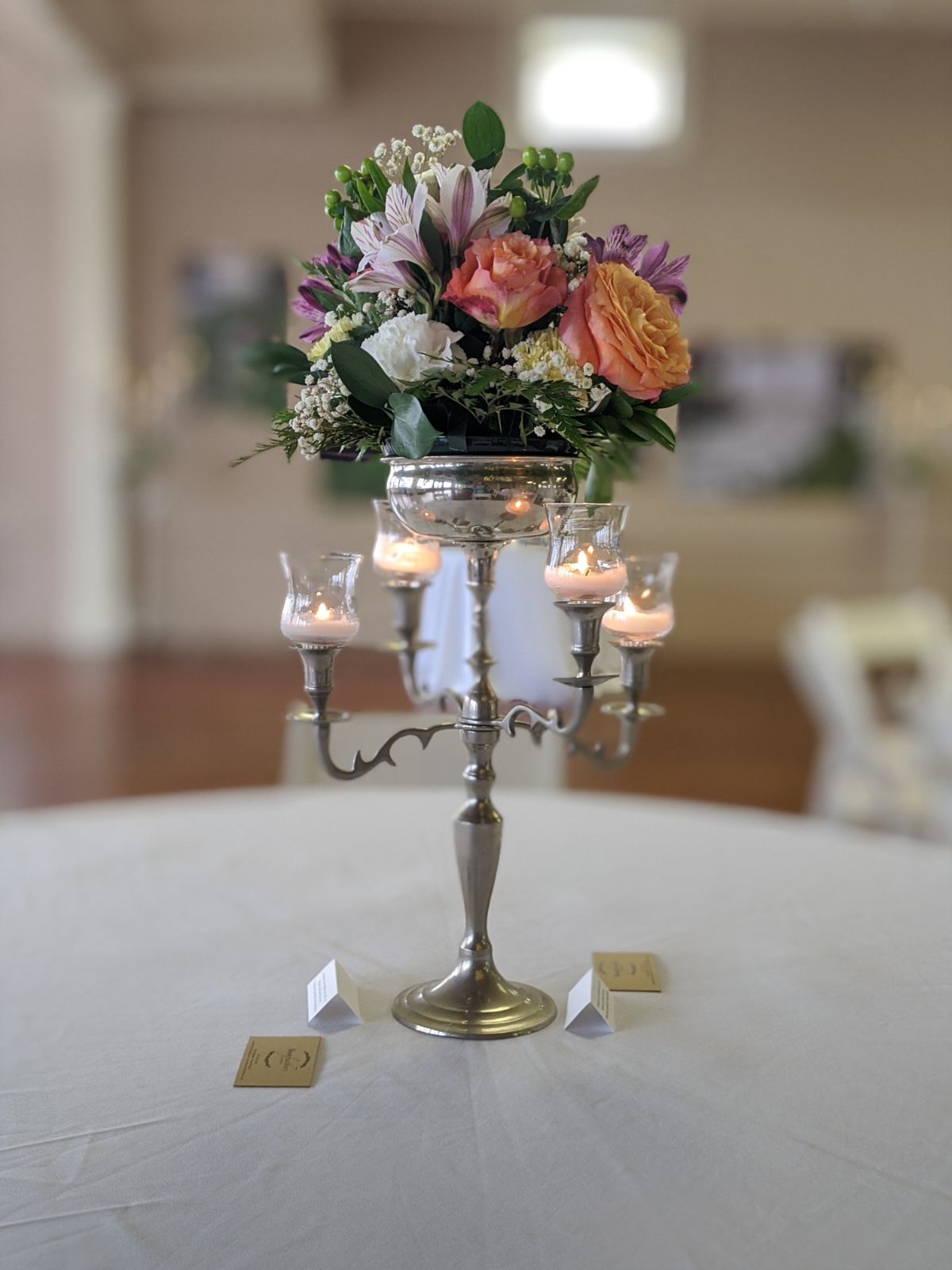 A table with a vase of flowers and candles on it.