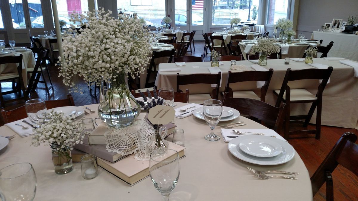 A table set for a wedding reception with a vase of baby 's breath on it.