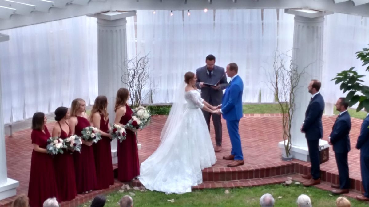 A bride and groom are holding hands during their wedding ceremony.