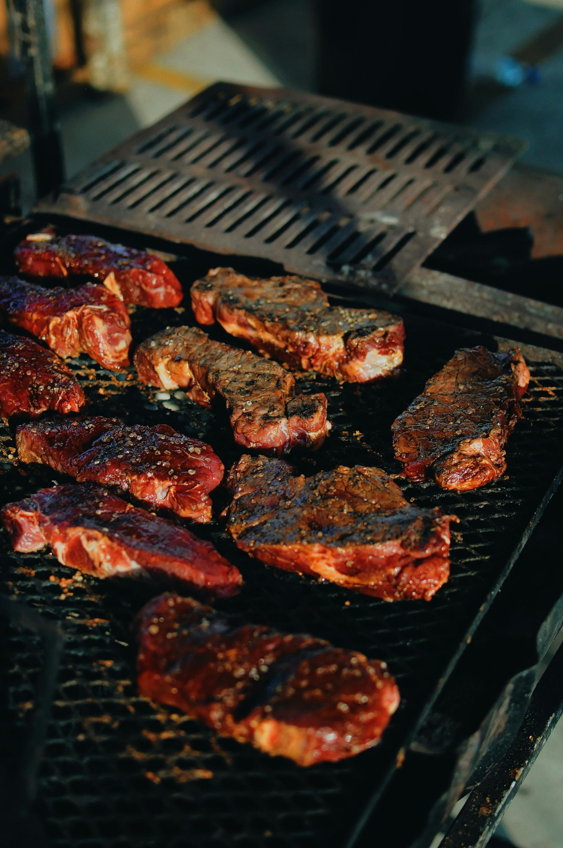 A bunch of meat is cooking on a grill.