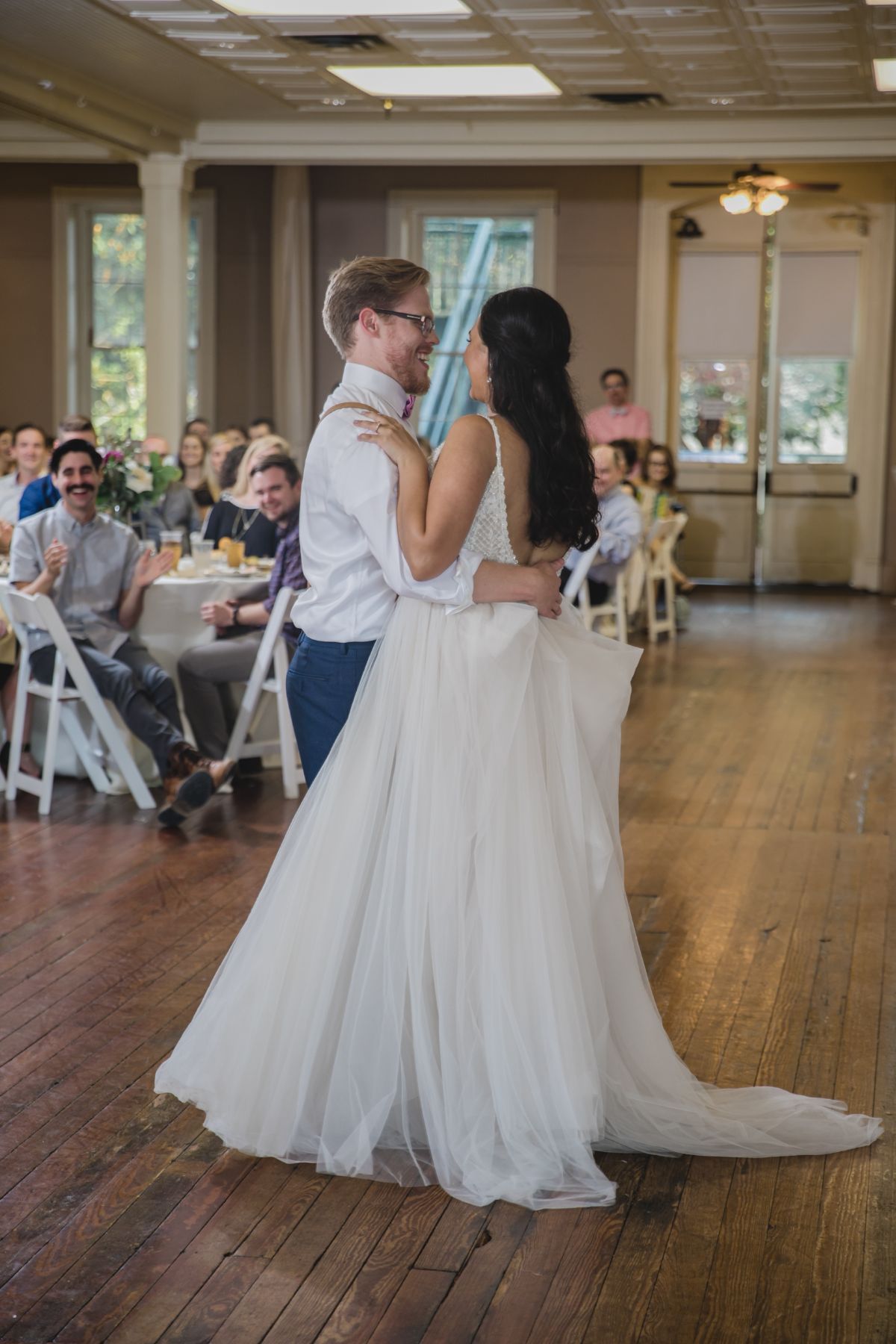 A bride and groom are dancing their first dance at their wedding reception.