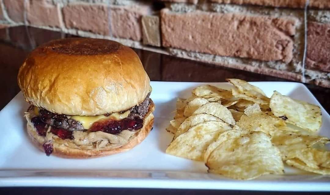 A hamburger and potato chips are on a white plate.