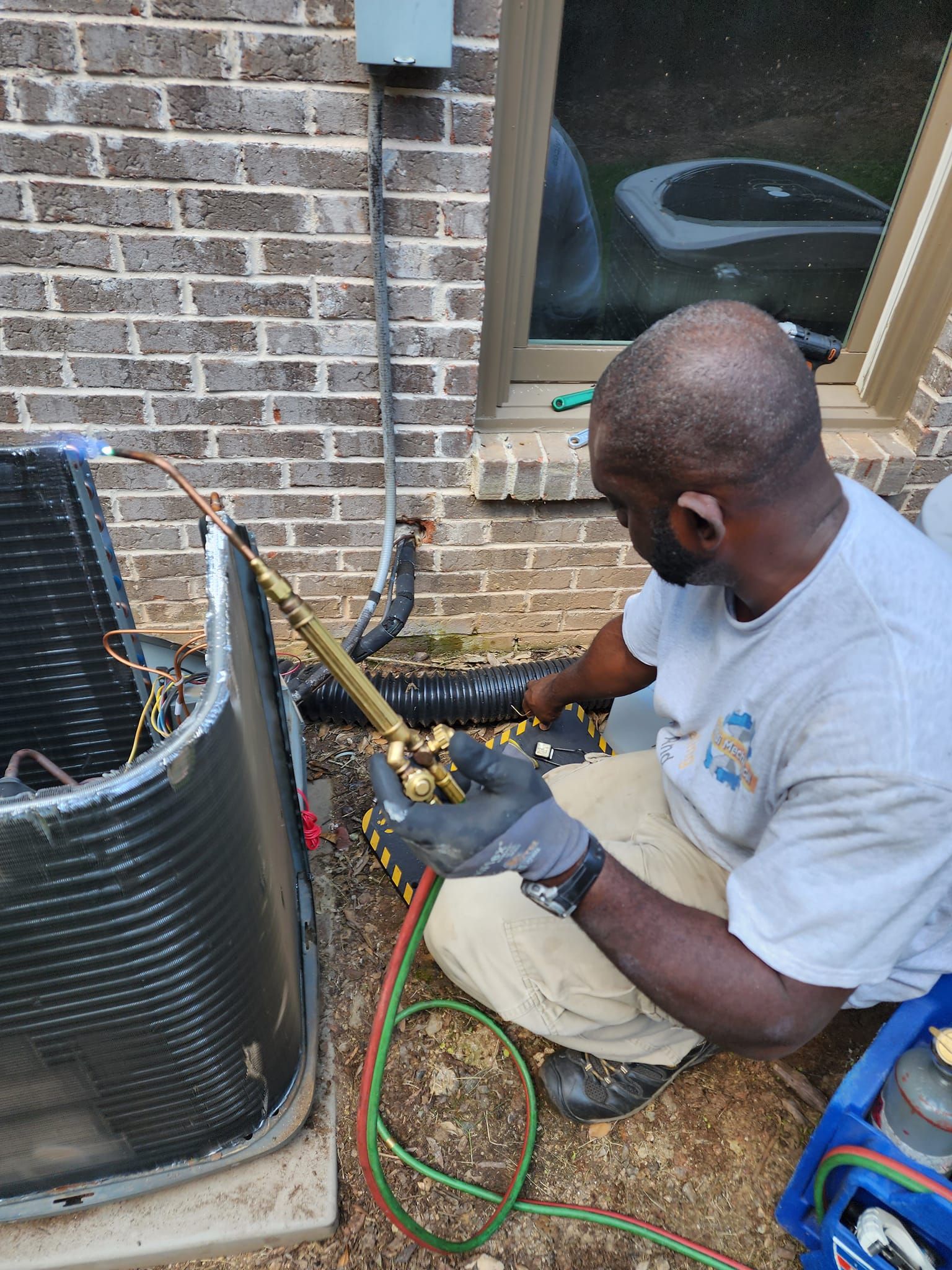 Technician in hard hat inspecting rooftop HVAC unit with a gauge meter