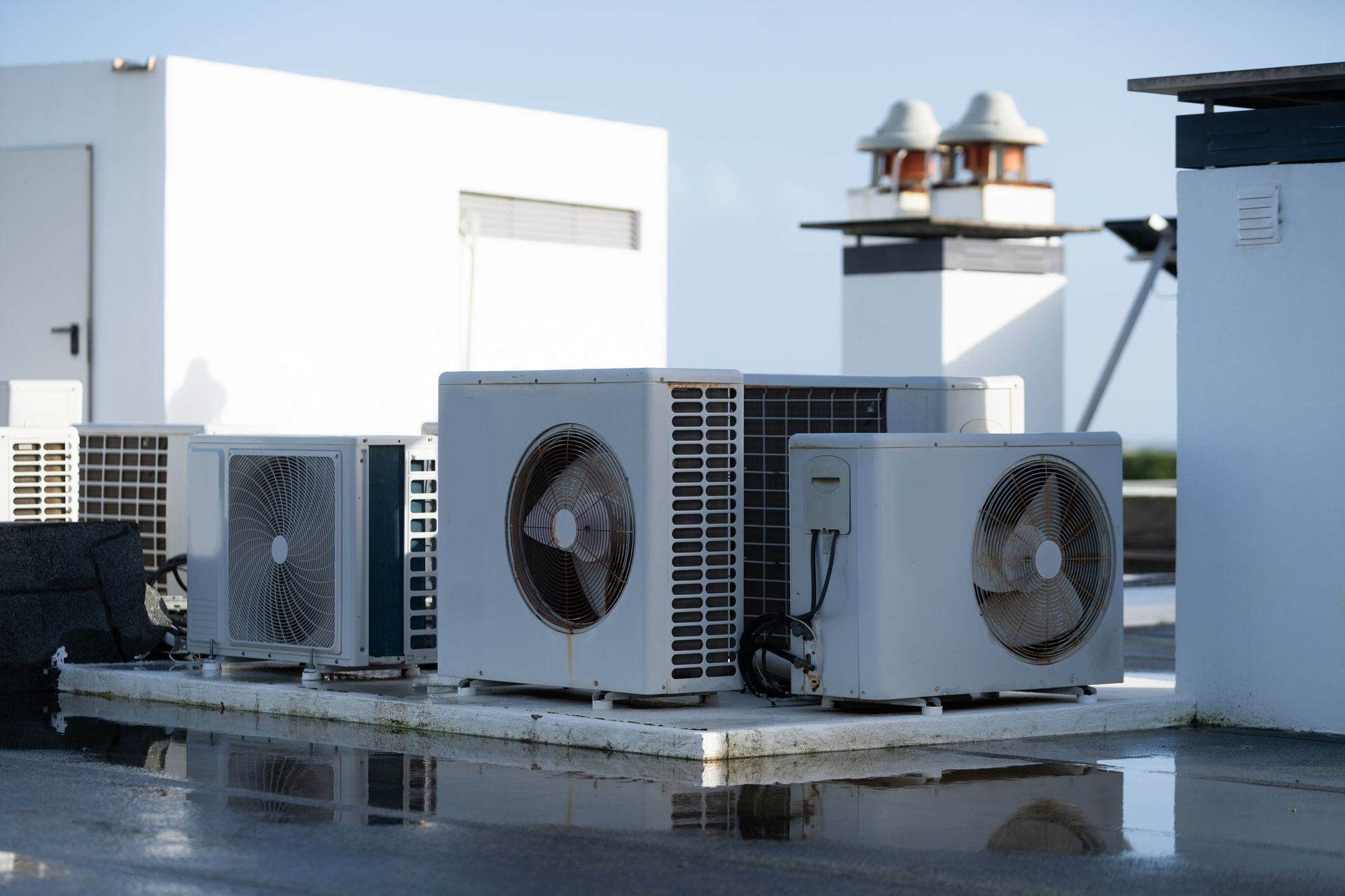Rooftop HVAC units and ventilation equipment on a flat white industrial building.
