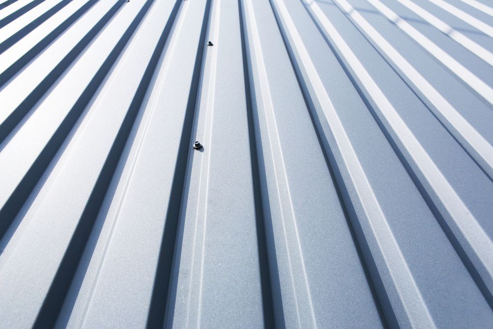 Metal roof with vertical ridges, silver-grey in color, with rivets.
