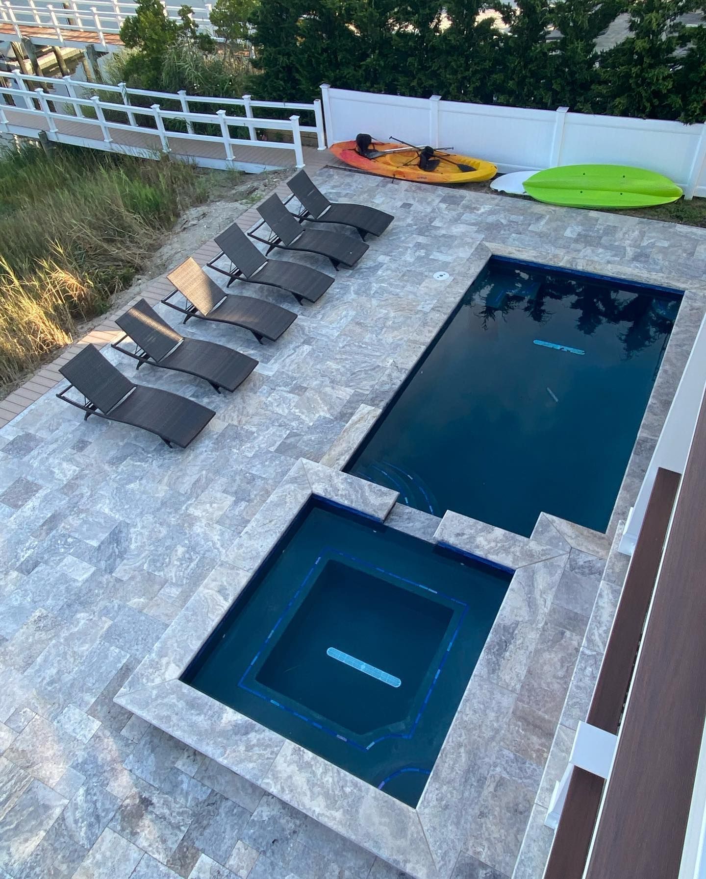 Overhead view of a pool and hot tub with lounge chairs, kayaks, and white fence built by j.k. construction llc in cape may county, new jersey