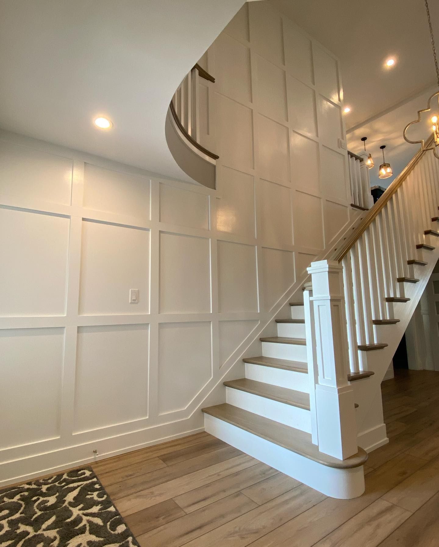 remodeled white-paneled wall and staircase with light wood steps. A patterned rug sits at the base remodeled by j.k. construction llc in stone harbor, new jersey