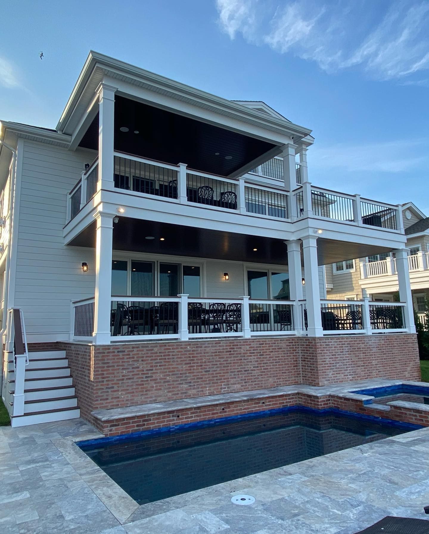 new built two-story house with pool, tan siding, red brick, and glass railings, overlooking a pool built by j.k. construction llc in ocean city, new jersey