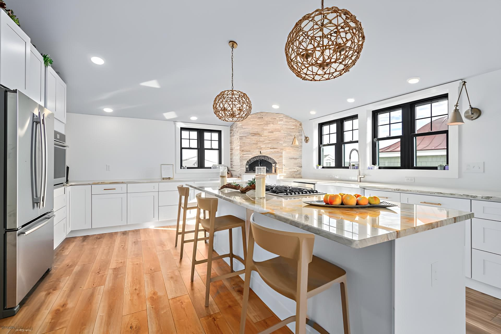 Bright kitchen with wooden floors, white cabinets, and an island with bar stools remodeled by j.k. construction llc in avalon, new jersey