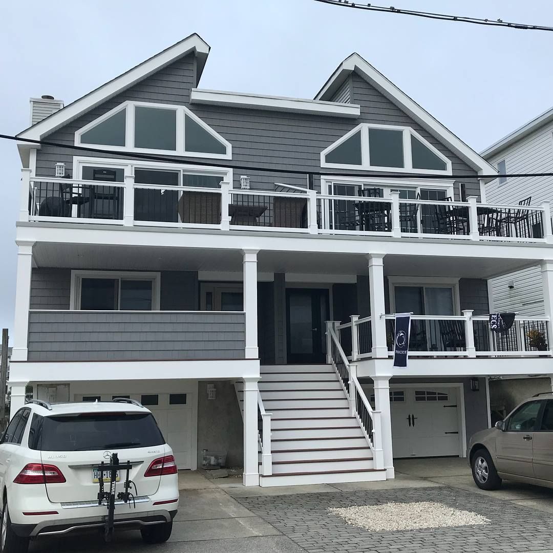 exterior renovation of two-story gray house with white trim, balconies, and garage doors by j.k. construction llc in stone harbor, new jersey