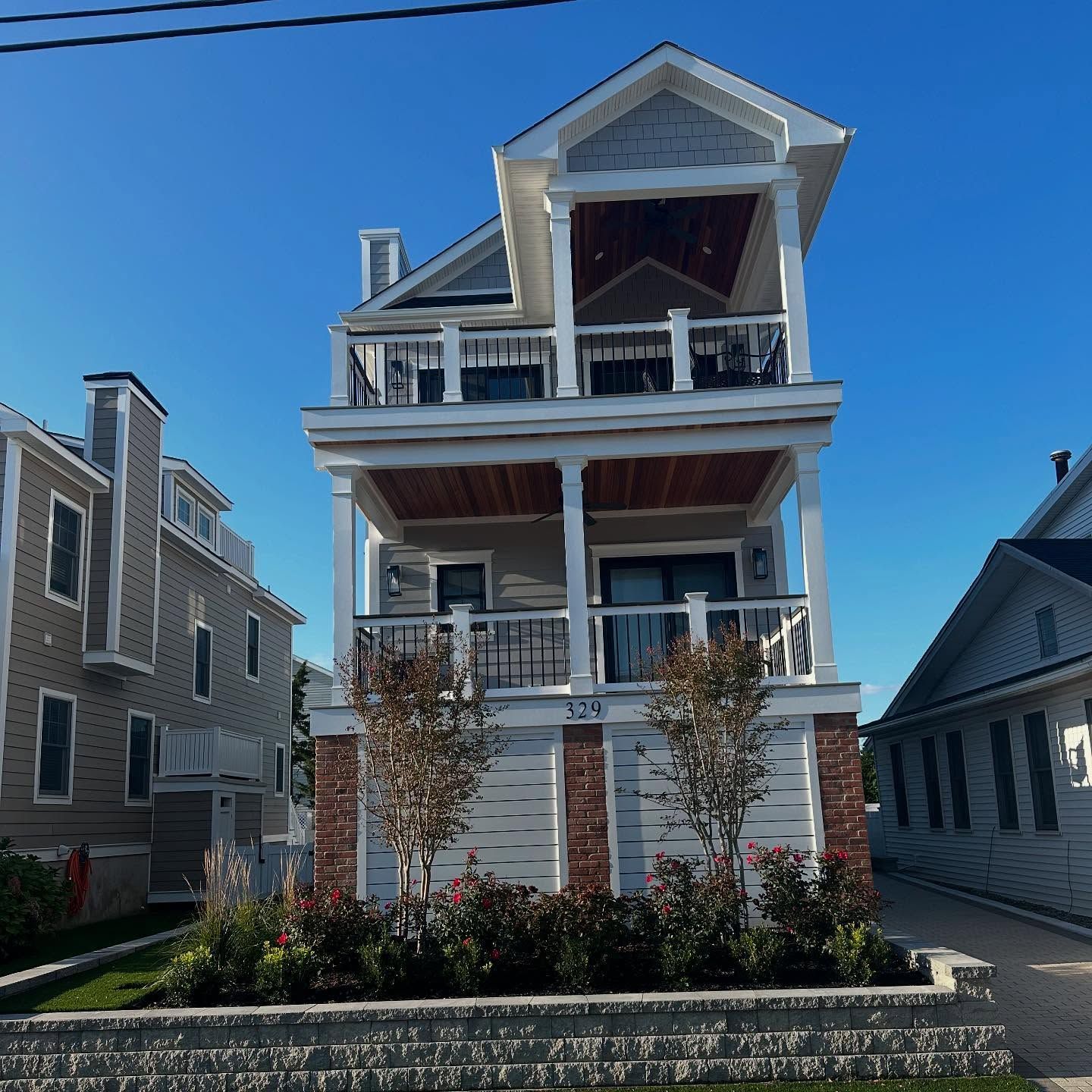 newly built two-story house with porch, gray siding, brick accents by j.k. construction llc in wildwood, new jersey