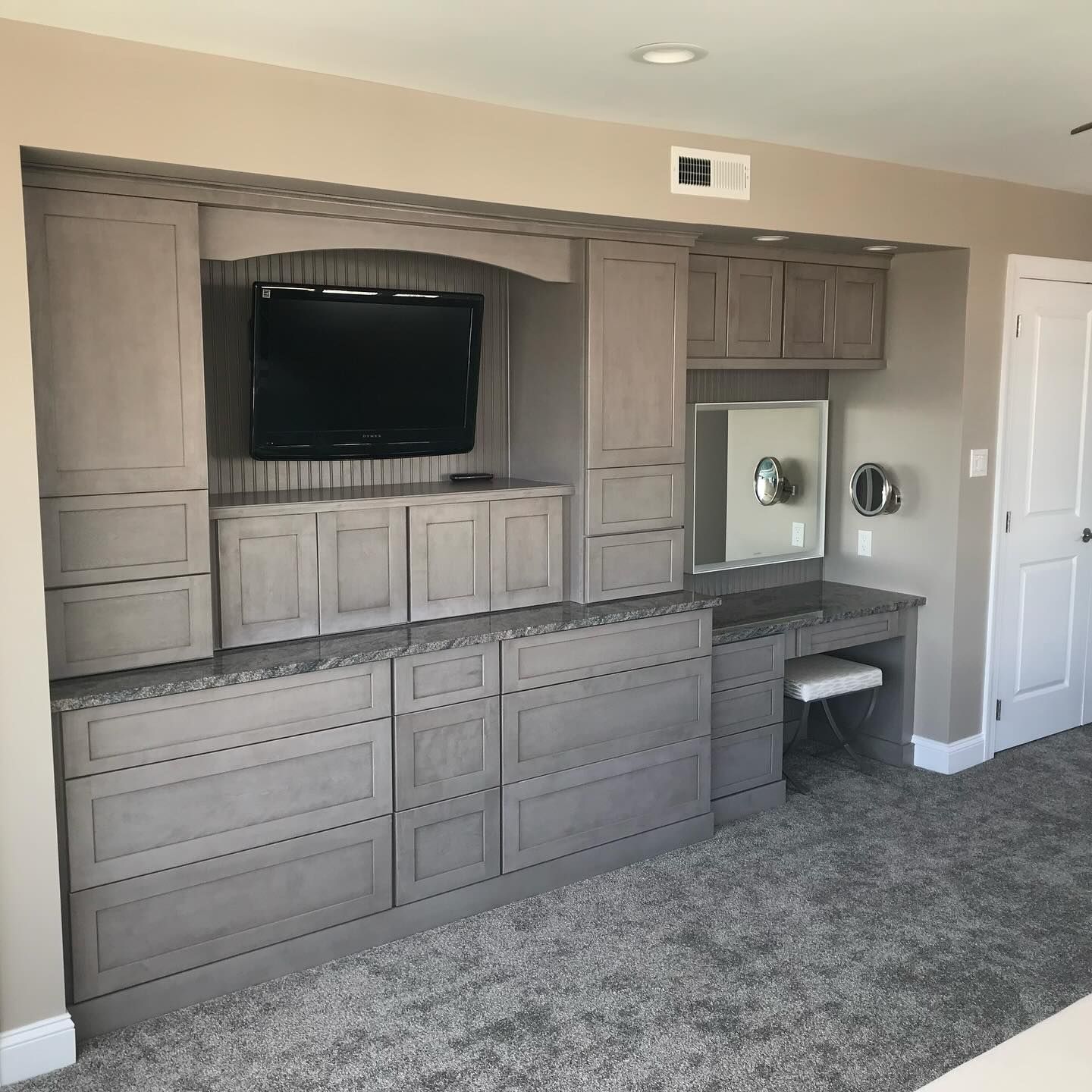 custom built-in gray storage cabinets with TV, vanity, and mirror in a bedroom built by j.k. construction llc in stone harbor, new jersey