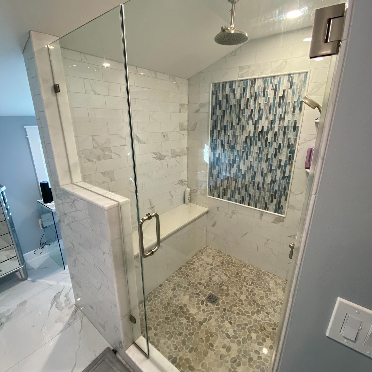 remodeled modern shower with glass door, marble tile, pebble floor, and blue mosaic tile accent by j.k. construction llc in ocean city, new jersey
