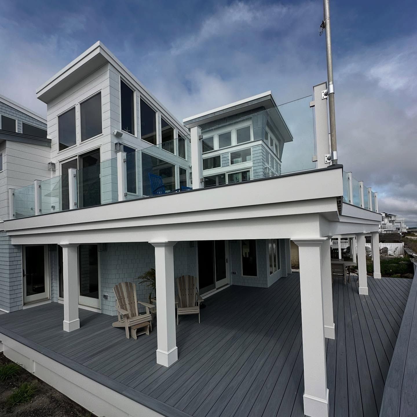 exterior remodel of a modern beach house with gray deck and blue exterior, glass railings by j.k. construction llc in avalon, new jersey