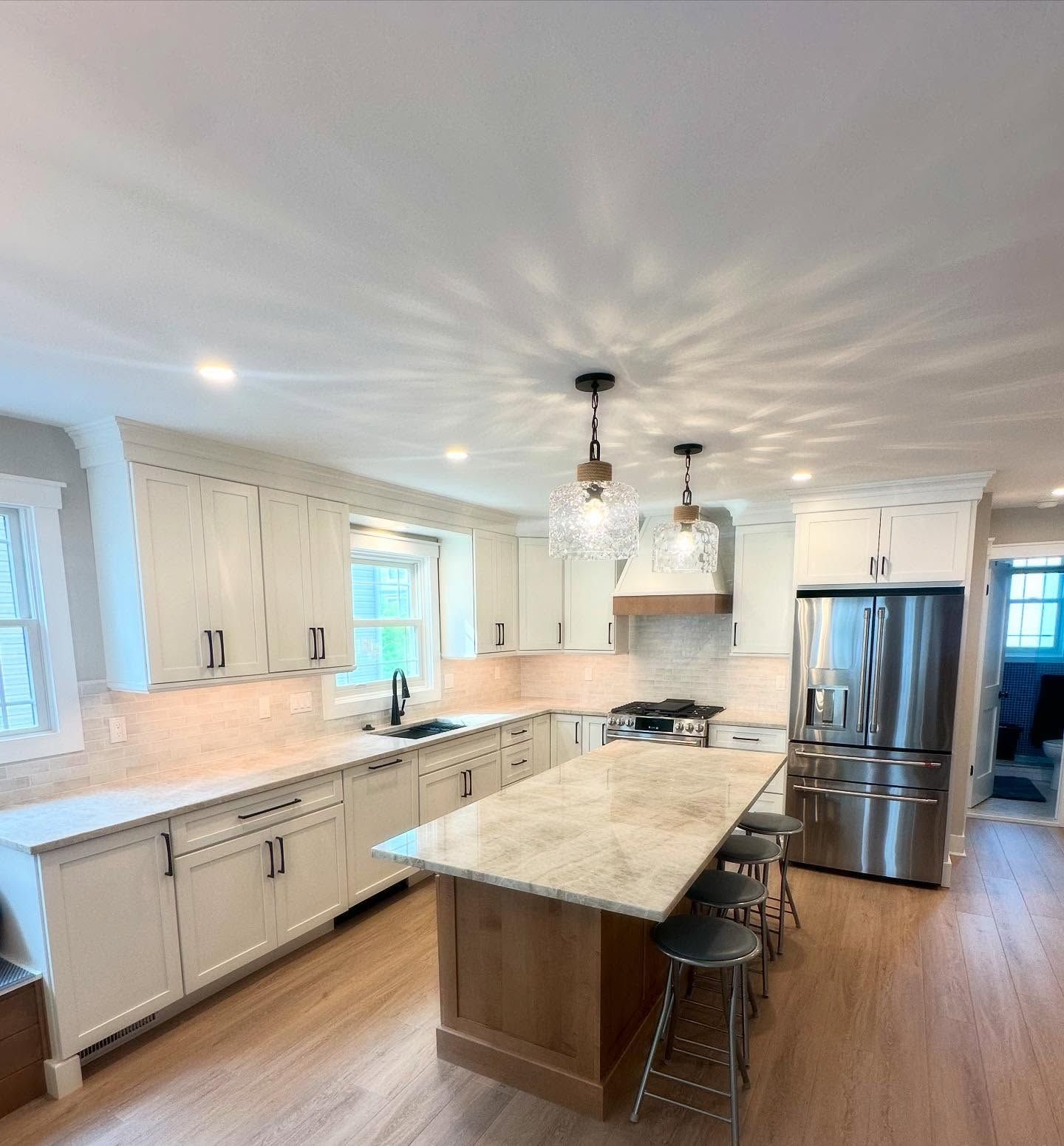 A remodeled modern kitchen with cream cabinets, a wooden island, stainless steel appliances, and pendant lights done by j.k. construction llc