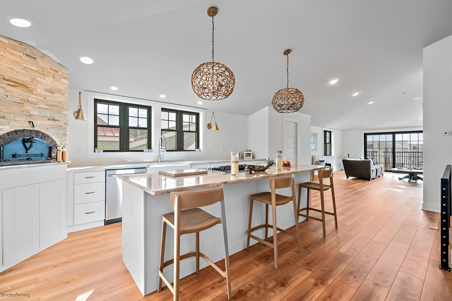 Bright kitchen with wooden floors, white cabinets, and an island with bar stools remodeled by j.k. construction llc in avalon, new jersey