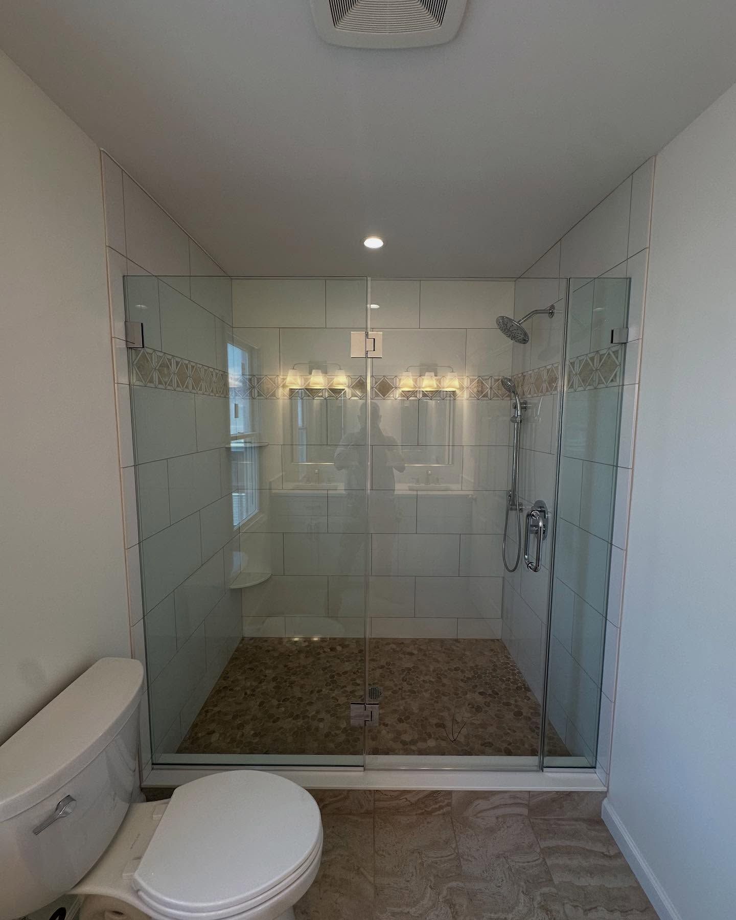 a new built modern bathroom with a glass-enclosed shower, stone floor, toilet, and white walls built by j.k. construction llc in cape may county, new jersey