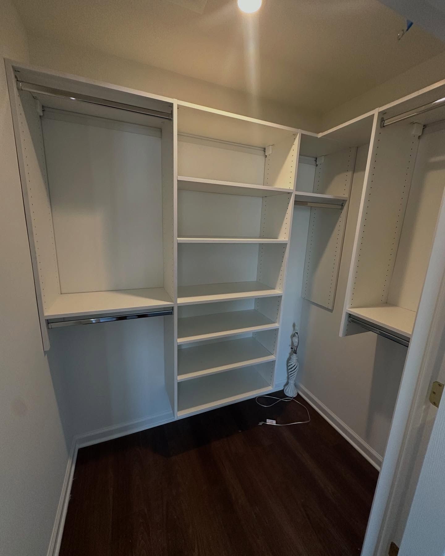 a new built empty white closet with shelves and hanging rods, dark wood floor built by j.k. construction llc in cape may county, new jersey