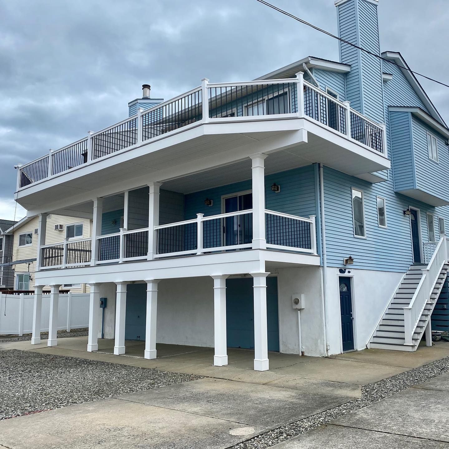 Exterior remodel of a shore house with light blue siding, white pillars and garage door in Cape May, NJ done by J.K. Construction LLC of Cape May Court House, NJ