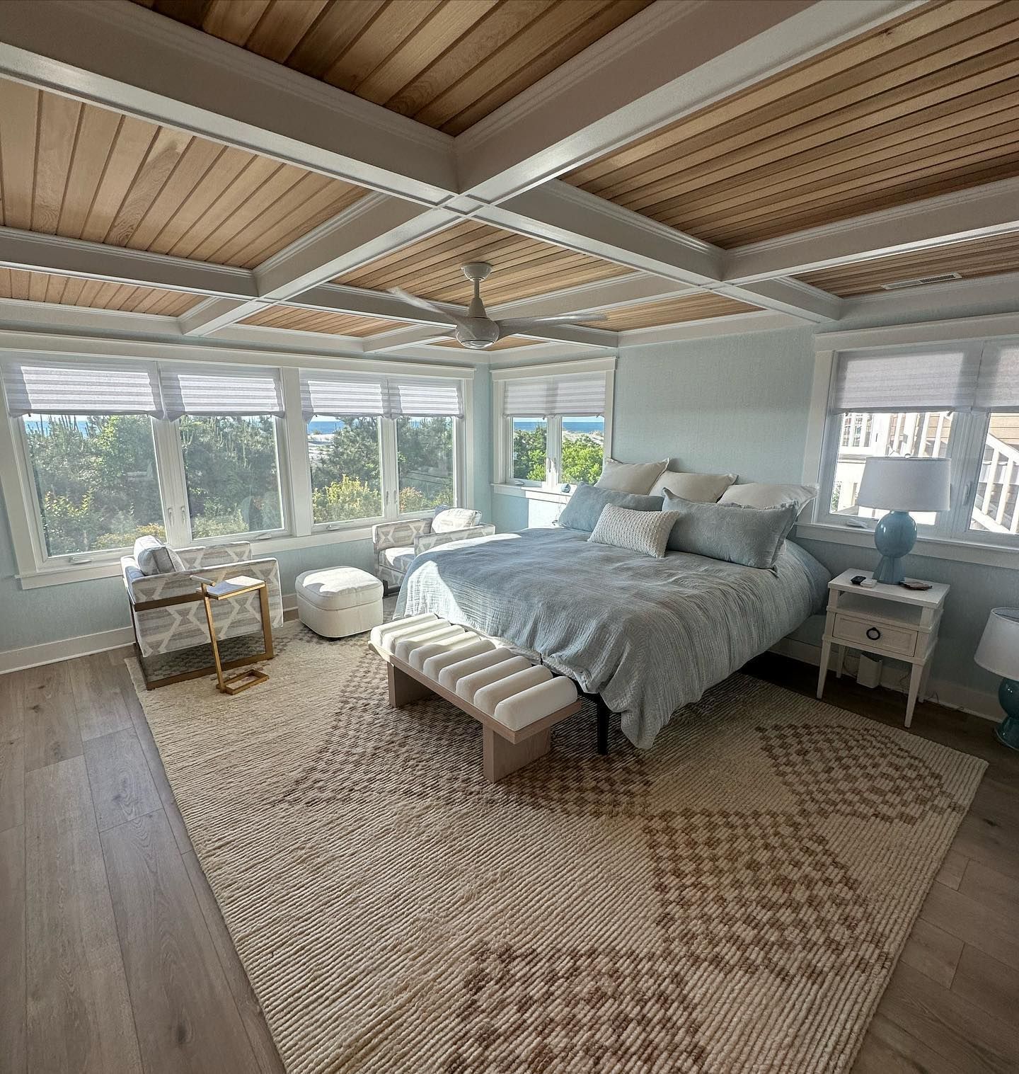 remodeled bedroom with light blue walls, wood ceiling, large windows, bed with blue bedding, and a patterned rug done by j.k. construction llc in sea isle city, new jersey