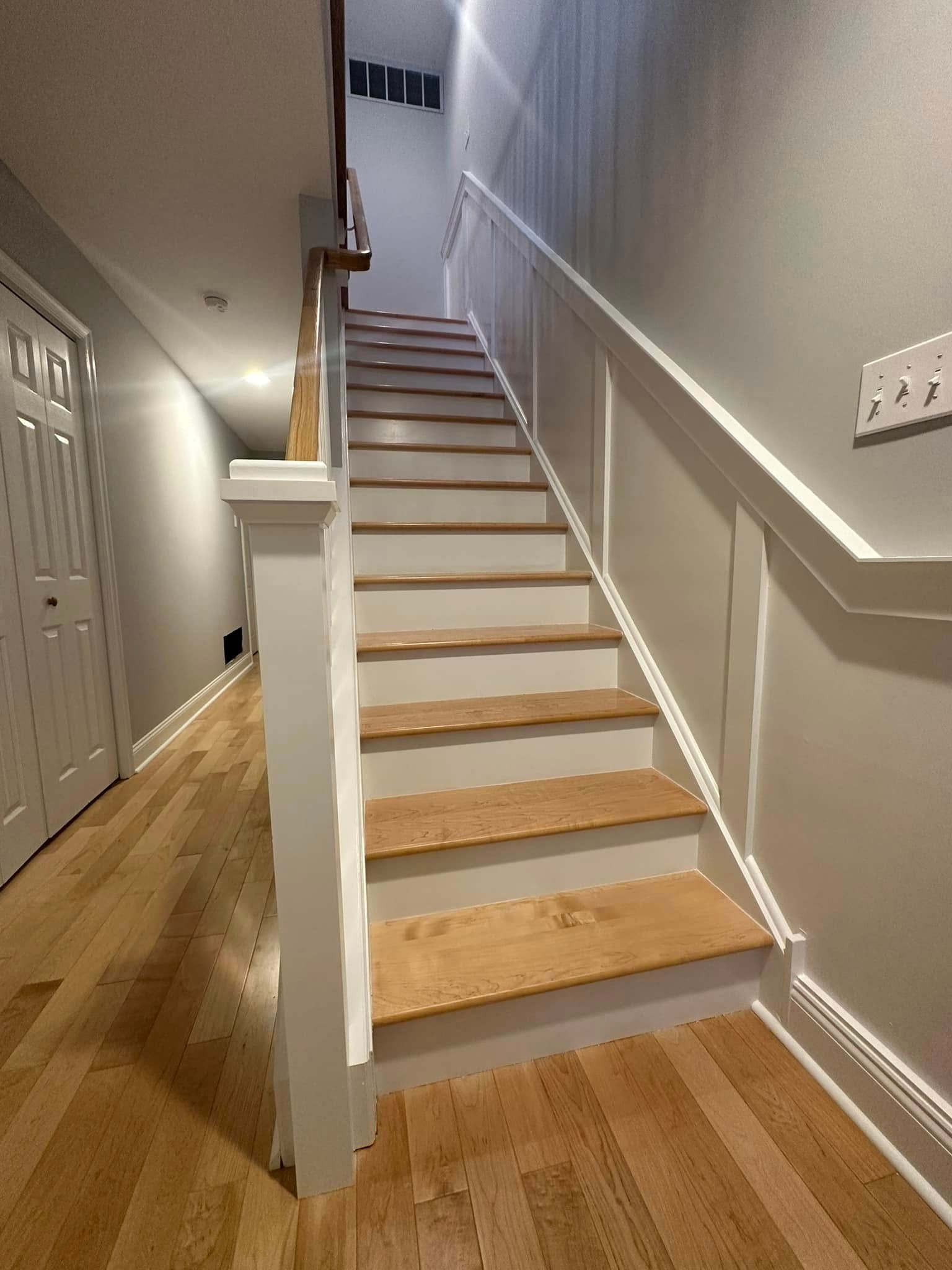 renovated, wooden staircase with white trim and handrail, leading to an upper level in strathmere, new jersey done by j.k. construction llc