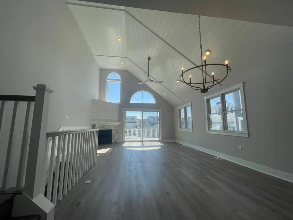 Spacious, bright living room with vaulted ceiling, chandelier, fireplace, and balcony access renovated by j.k. construction llc