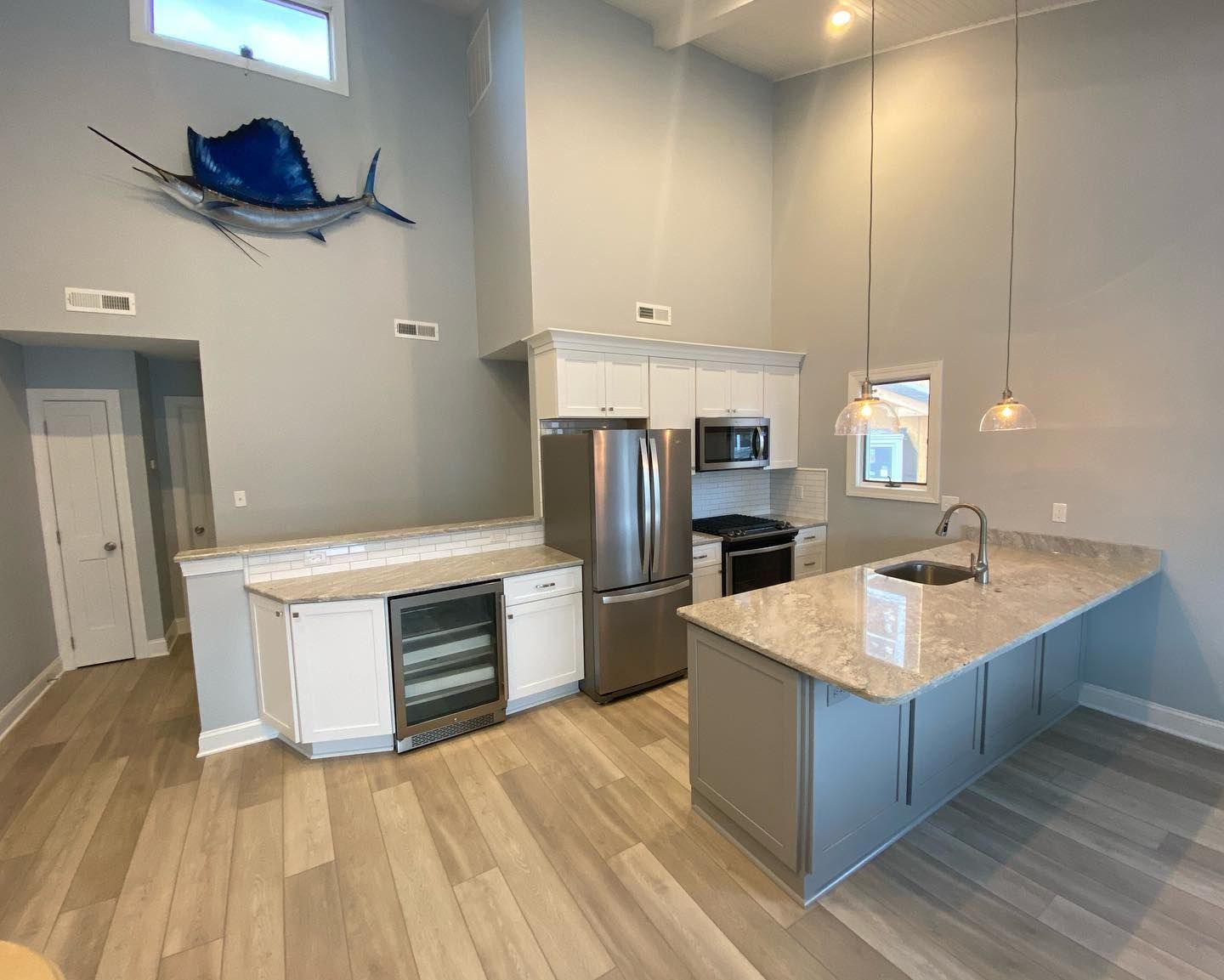 Modern kitchen with light wood floors, stainless steel appliances, and a large sailfish sculpture remodeled by j.k. construction llc