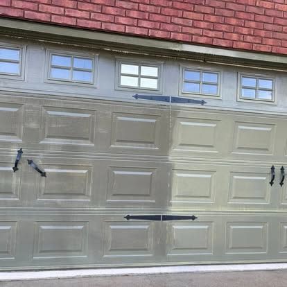 Garage door with rectangular panels and four small windows, tan with black hinges and handles.