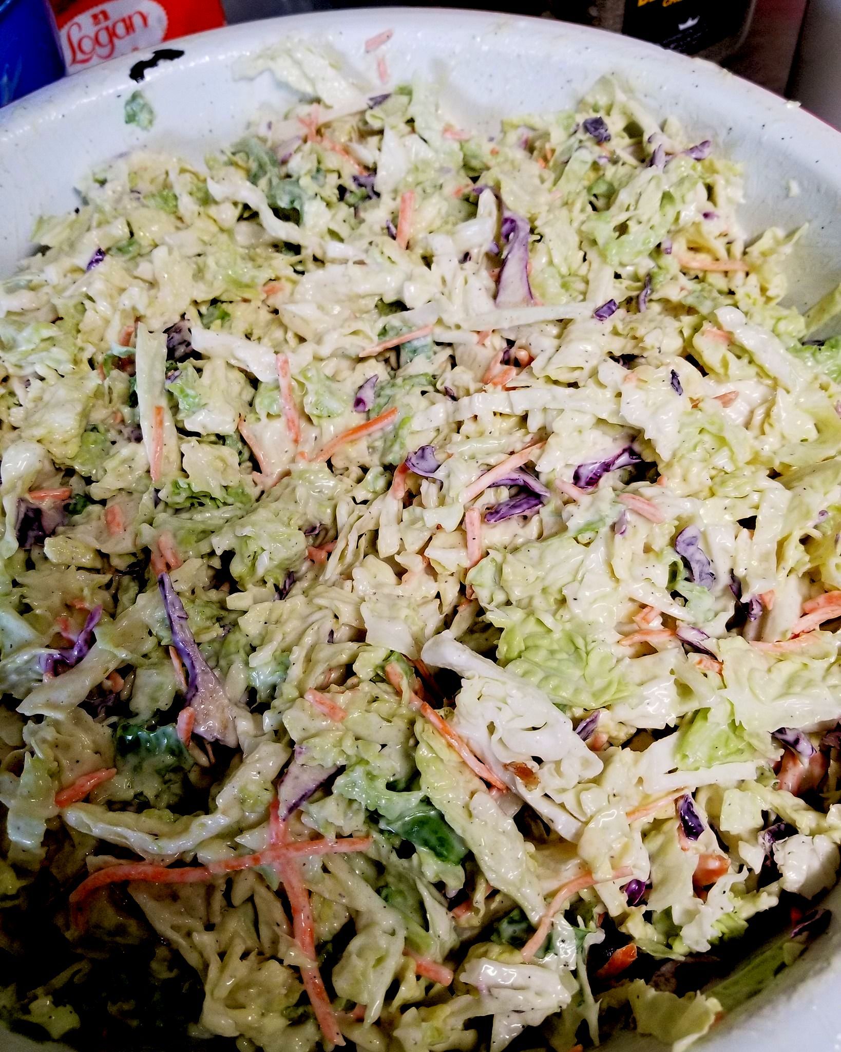 A close up of a bowl of coleslaw with carrots and cabbage.
