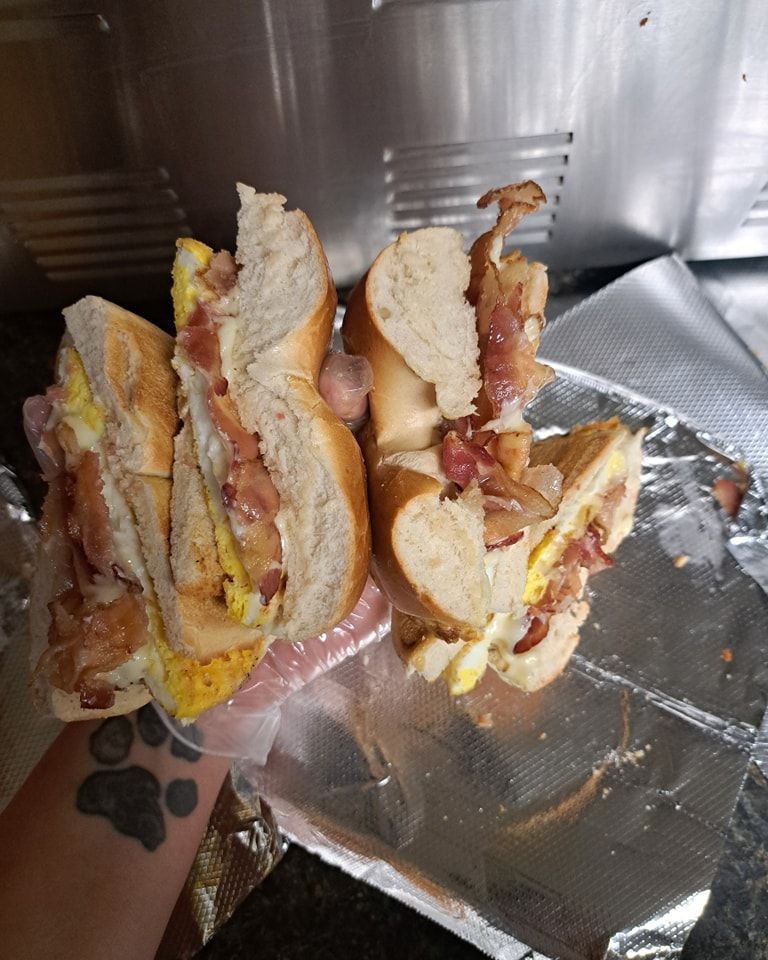 A person with a tattoo on their arm is holding two sandwiches