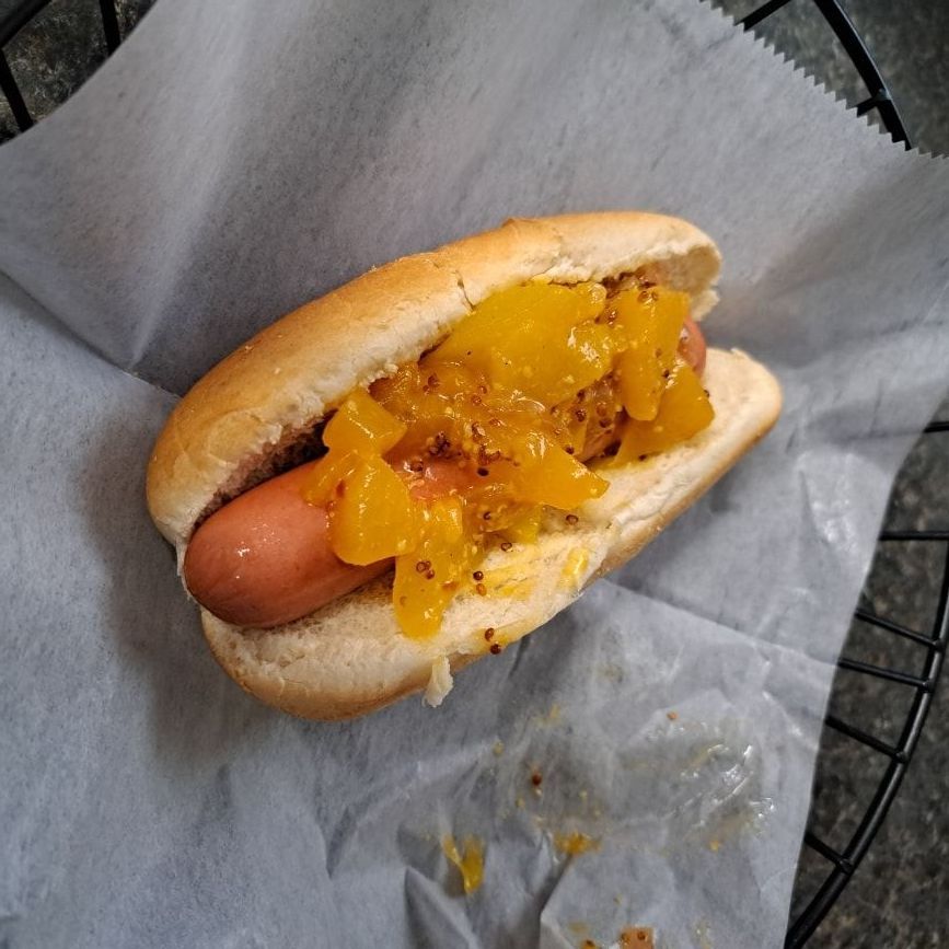 A close up of a hot dog on a bun on a piece of paper.