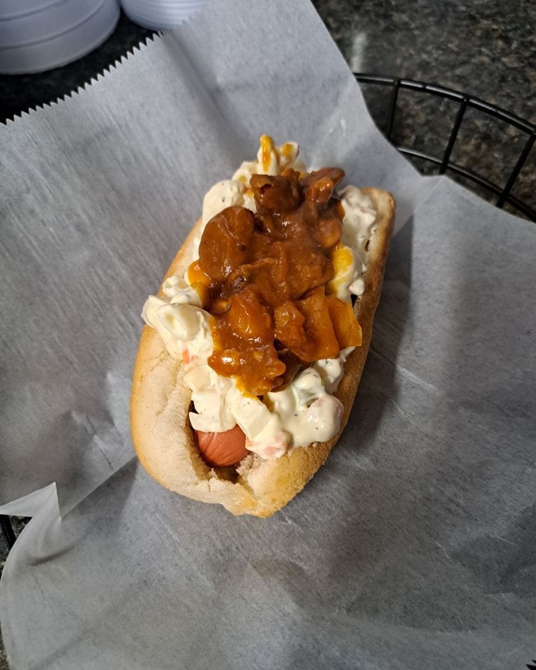 A hot dog with coleslaw and sauce on a bun.