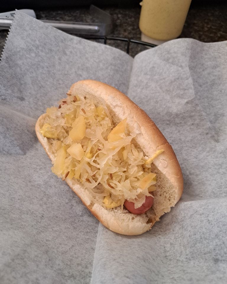 A hot dog with sauerkraut and cheese on a bun