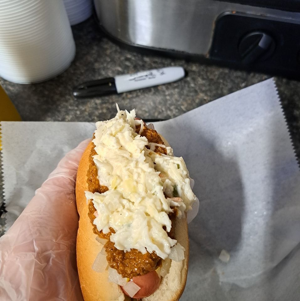 A person is holding a hot dog with coleslaw on top