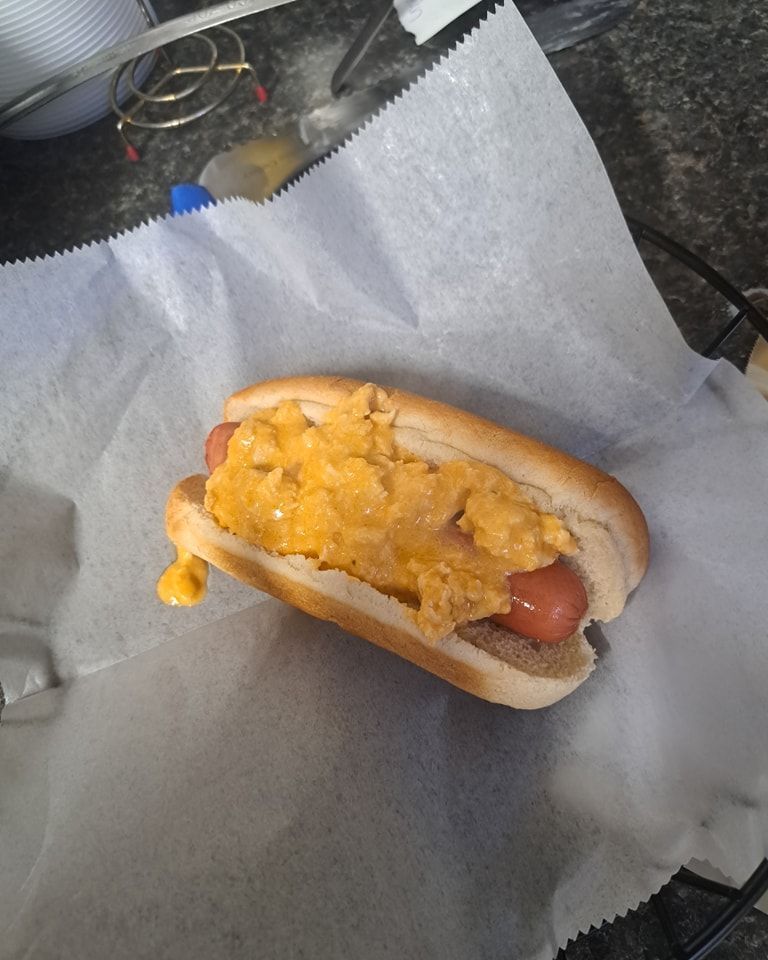 A hot dog on a bun with cheese on it