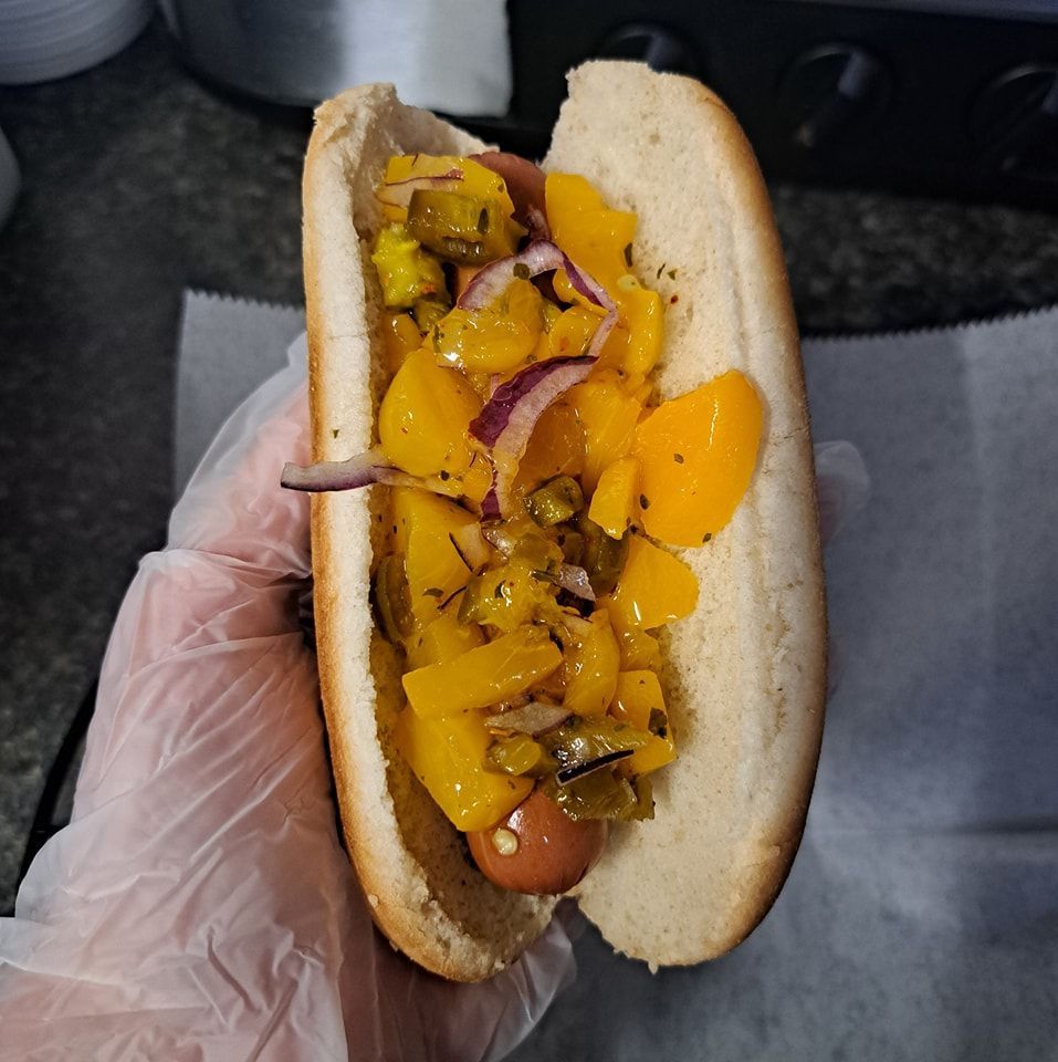 A person is holding a hot dog with pickles on it