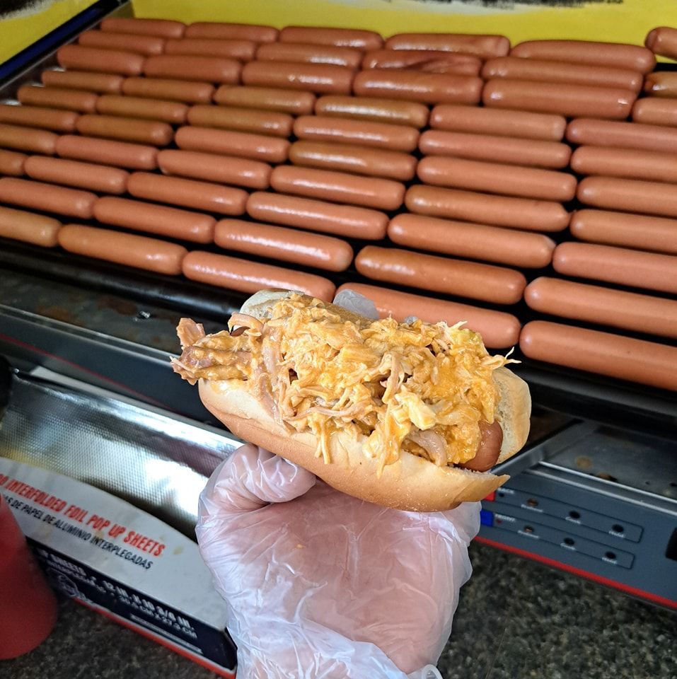 A person is holding a hot dog in front of a bunch of hot dogs