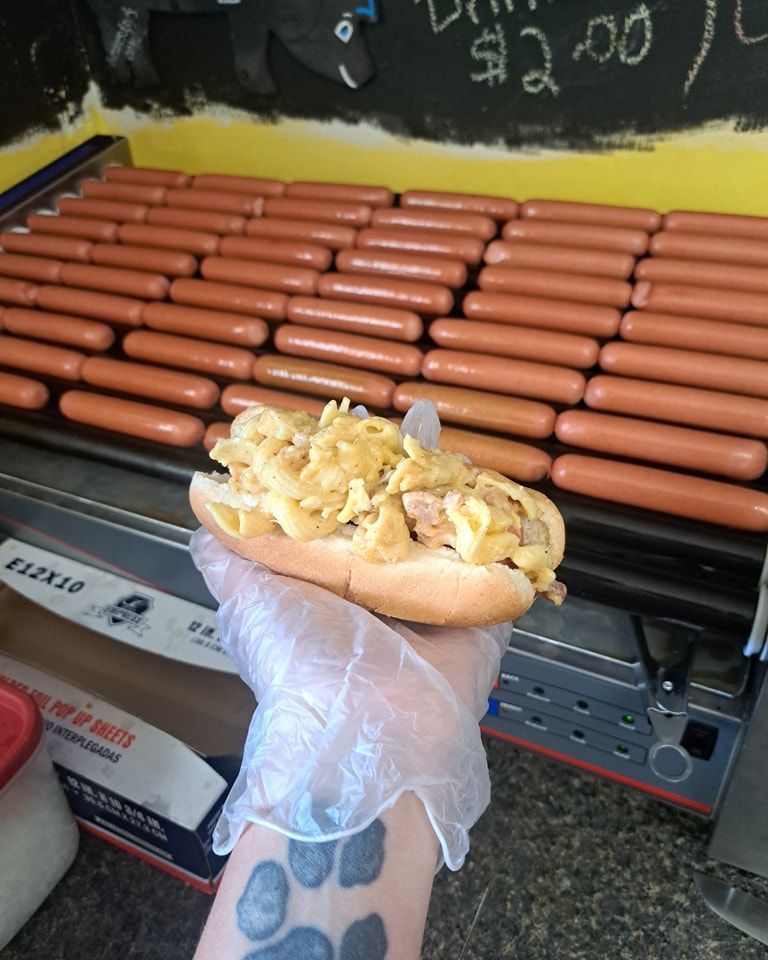 A person is holding a hot dog in front of a bunch of hot dogs