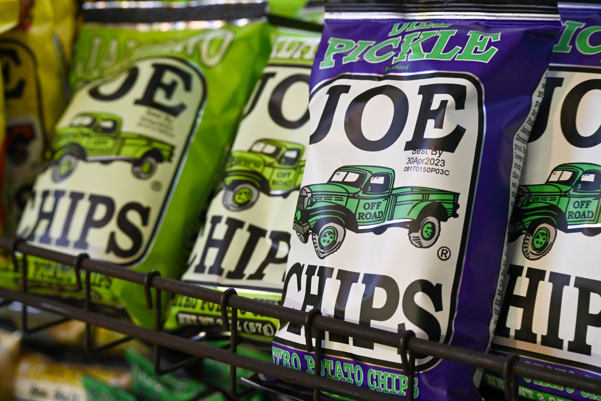 Several bags of joe pickle chips are lined up on a shelf