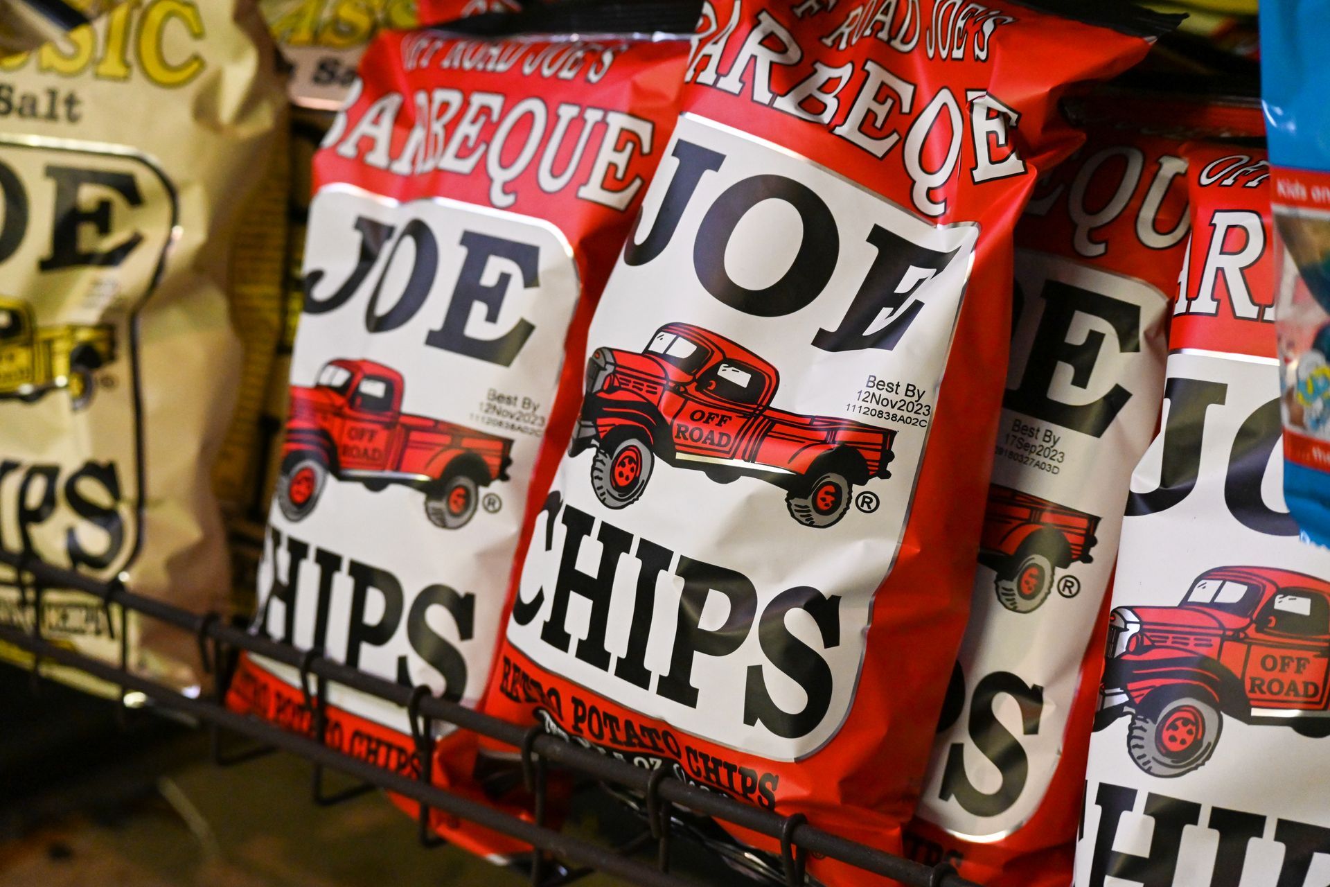 A bunch of bags of barbeque joe chips are sitting on a shelf.