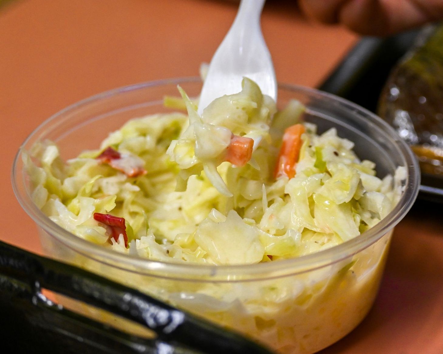 A bowl of coleslaw with a fork in it