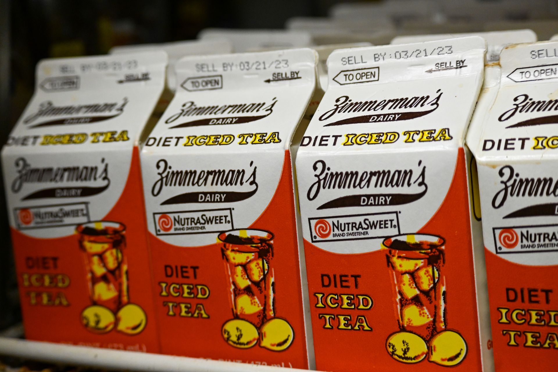 Several cartons of jimmerman 's diet iced tea are lined up on a shelf