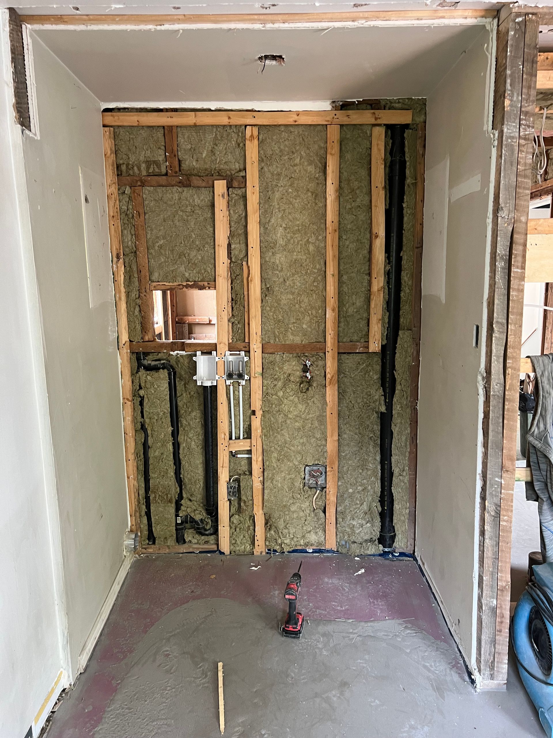 Une pièce en cours de rénovation avec une perceuse au sol.