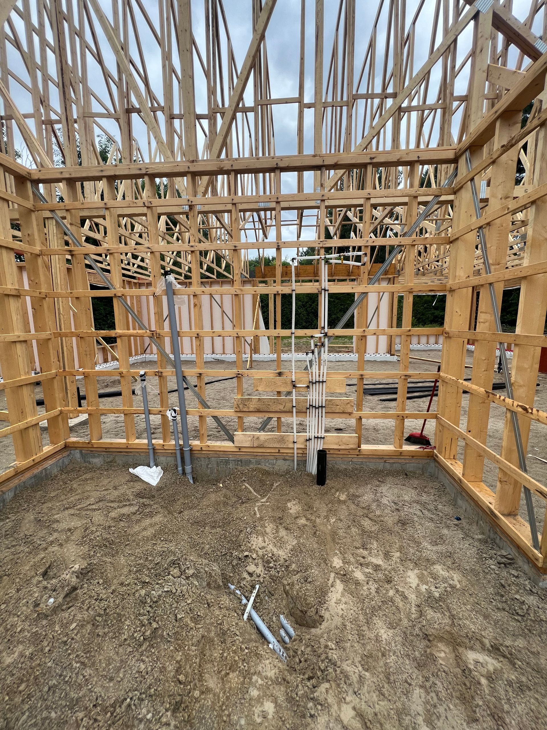 Une structure en bois est en cours de construction sur un terrain en terre.