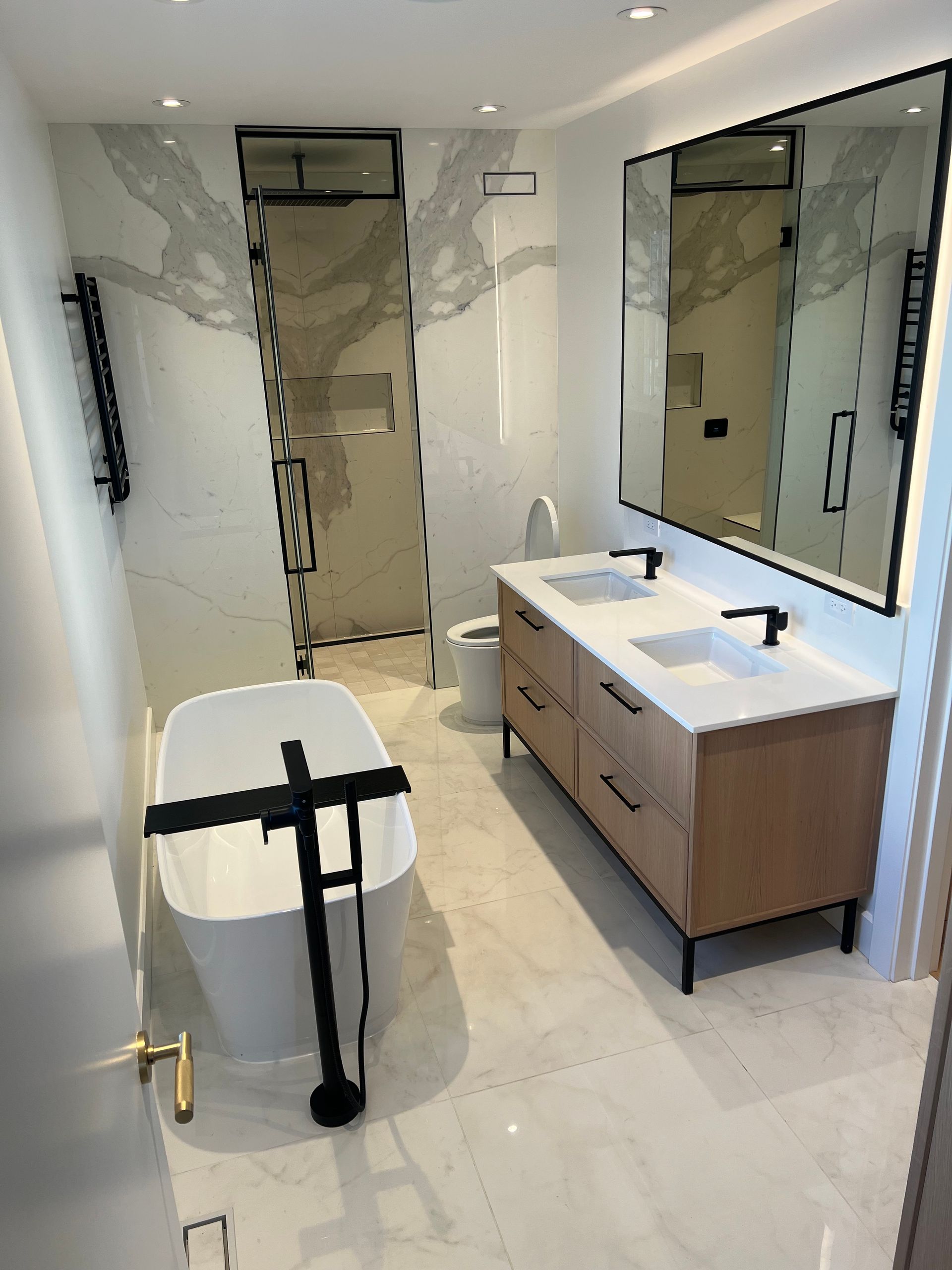 Une salle de bain avec baignoire, lavabos, toilettes et miroirs.