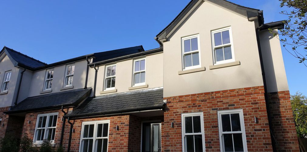 A large brick house with a lot of windows and a blue sky in the background.
