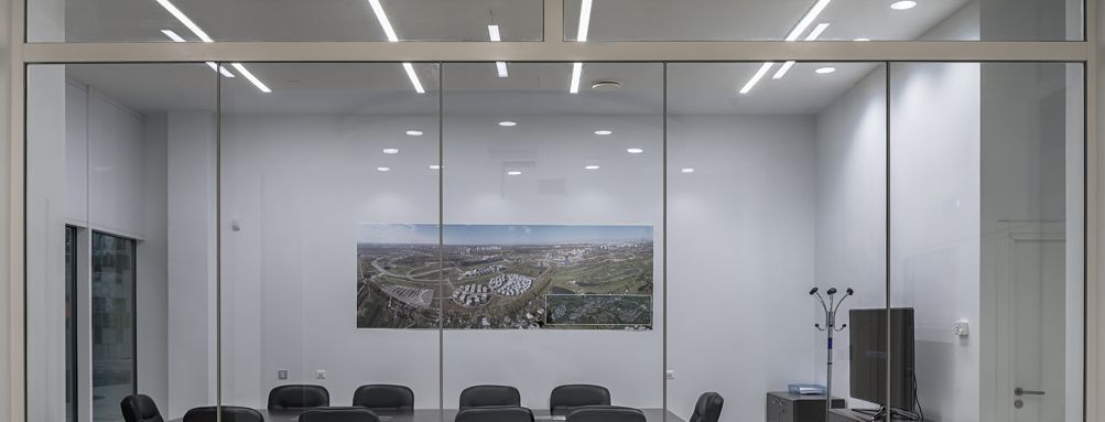 A conference room with a glass wall and a table and chairs.