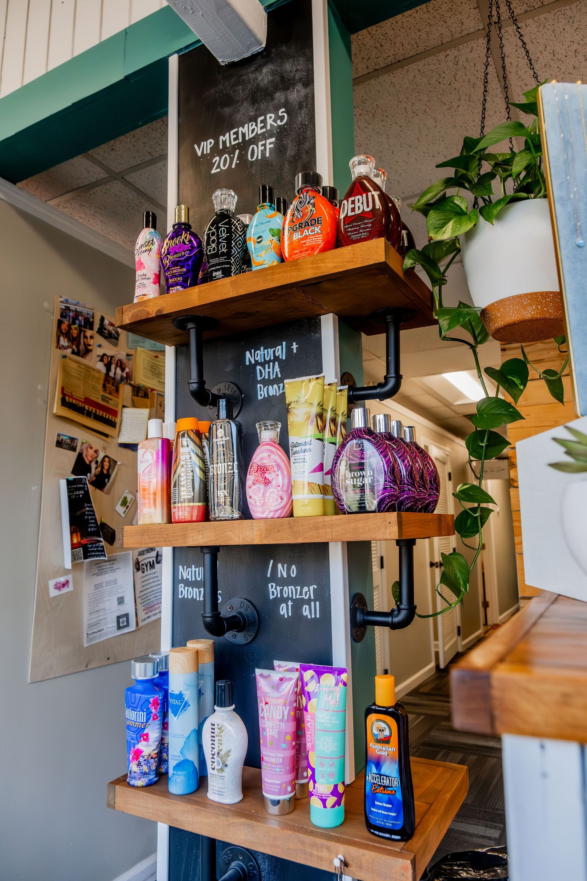 Shelves displaying various tanning lotions and products in a salon. Wooden shelves are supported by black pipes against a painted black pillar.